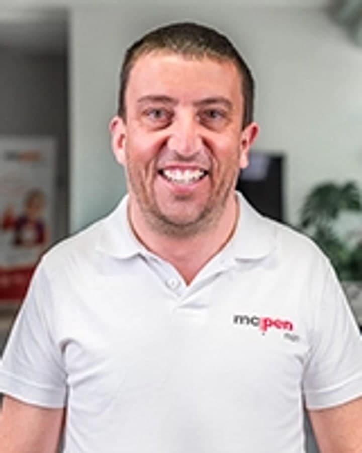 Jiří Kajzner. Usměvavý muž kolem padesátky v bílé polokošili, vyfotografovaný v interiéru prodejny.